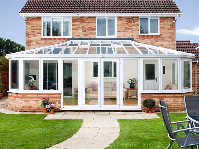 Large white conservatory on brick two storey home