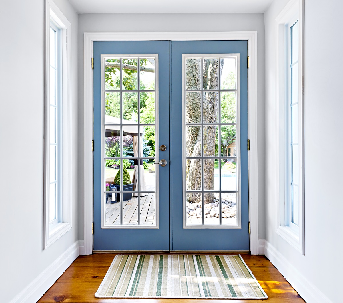blue framed glass doors with doormat and tree