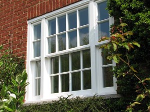 white timber sash windows framed by plants and red bricks