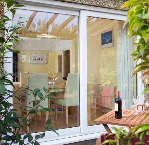 White patio door beside wooden table with wine bottle and glasses