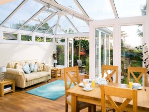 Furniture inside sunny conservatory with glazed roof