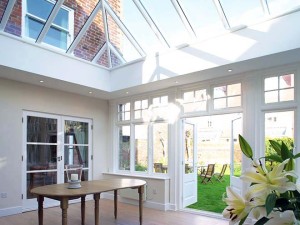 Interior of timber conservatory with open french doors and flowers