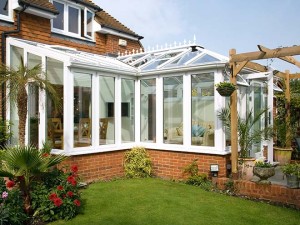 white upvc conservatory with brick base, patio and lawn