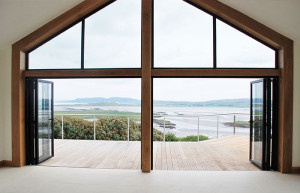 open bifold doors in large wooden frame with panoramic view of water