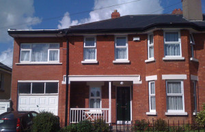 brick two storey house with white framed casement windows