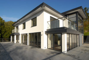 White two-storey house with full length glazing and glass balustrade