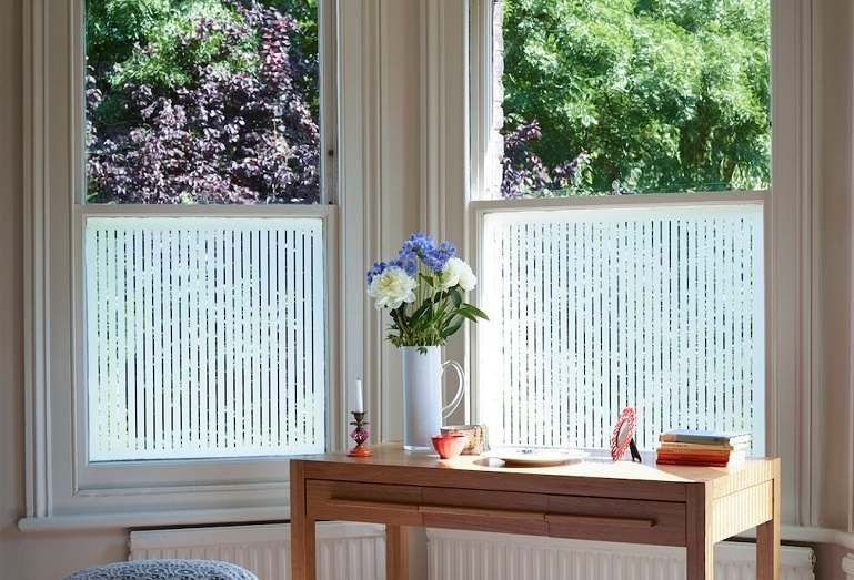Window film on bedroom windows, table and vase with flowers