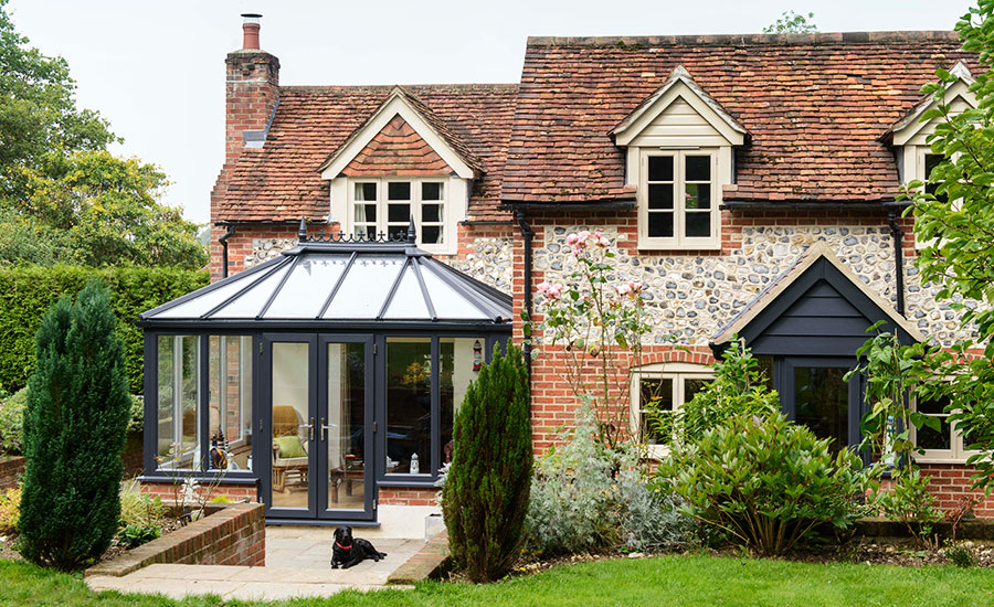grey wooden conservatory beside brick home